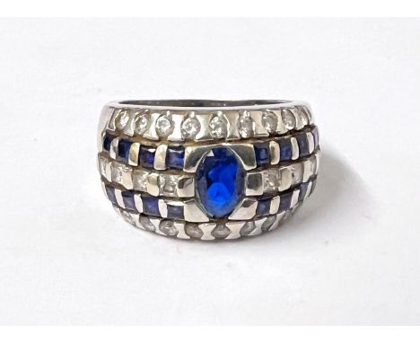A white ....... ct hallmarked white gold ring set with central blue stone with blue and clear stones in rows to each side siz