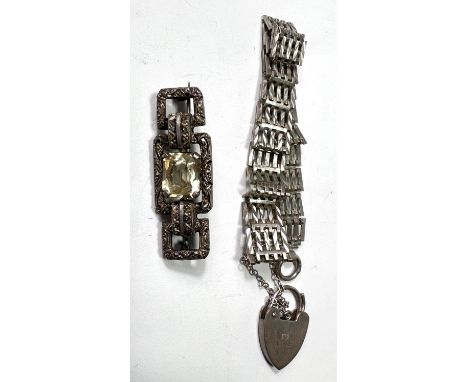 A white metal gate bracelet with heart lock; an Art Deco white metal brooch set with a cushion cut clear stone 