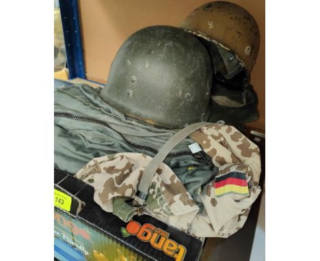 An M1 WWII style American composition helmet with strapping inside, a large green military style overcoat; A M1 style helmet 