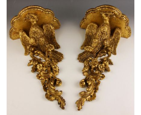 A pair of George II style carved giltwood wall brackets, 19th century, each with a scalloped moulded shelf over an eagle perc