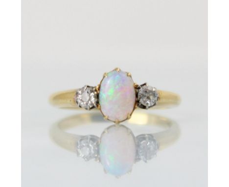 An early 20th century opal and diamond three stone ring, the central oval opal cabochon with old cut diamond to each side, se