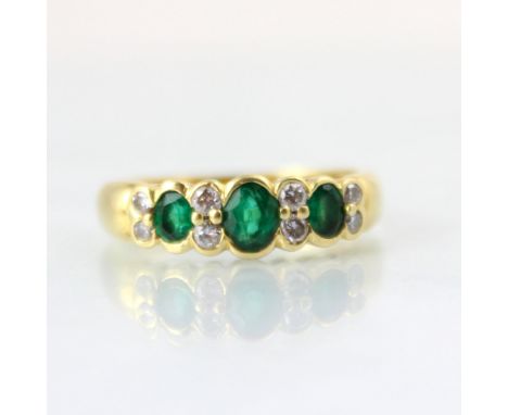 A mid 20th century untested emerald and diamond ring, the central oval cut untested emerald with two small round cut diamond 