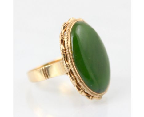 A yellow metal nephrite dress ring, the oval shaped cabochon within a yellow metal bamboo style mount, leading to plain polis
