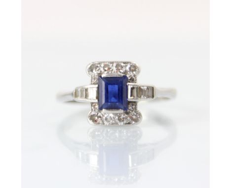 An Art Deco diamond and untested sapphire ring, the central rectangular cut untested sapphire within surround of twelve round