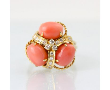 A coral and diamond dress ring, the trefoil designed head set with three cabochon coral with diamond set yellow metal detail,