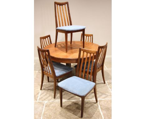 A mid 20th century G Plan teak dining table with six chairs, the circular table with fold out leaf and makers label to the un