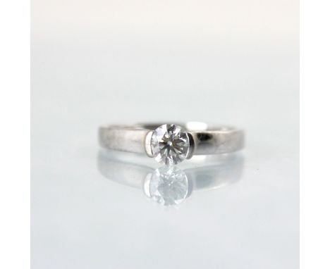 An 18ct white gold diamond solitaire ring, the central brilliant cut diamond within partial rub over mount leading to plain p