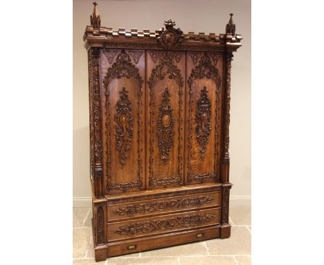 A Scottish baronial oak hall cupboard, late 19th century, the castellated cornice and Gothic spire finials centred with a cir