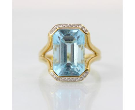 An 18ct yellow gold diamond and untested blue topaz dress ring, the central emerald cut untested blue topaz within openwork h