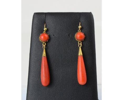 A pair of 19th century coral drop earrings, the round cabochon coral within cut down setting edge, suspending a torpedo shape