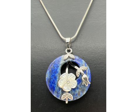 A modern design circular Lapis Lazuli pendant with floral mother of pearl set overlay on a 24 inch fine snake chain with lobs