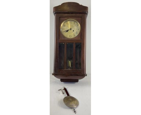 A vintage dark oak cased wall hanging, swinging pendulum clock. Complete with key &amp; pendulum. With metal dial and domed s