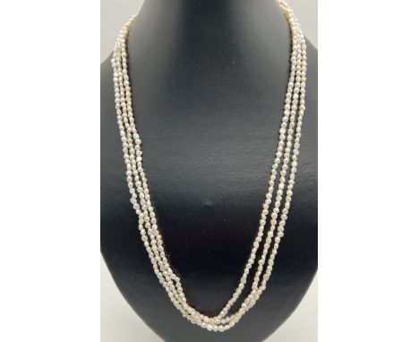 A 22 inch 3 strand small baroque pearl necklace with gold tone pierced work clasp. 