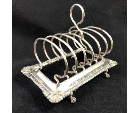 Ornate H M Silver Toast Rack - a four ball and claw footed 6 division toast rack with gadrooned edge and scallop shell corner