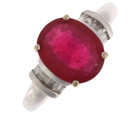 A modern 18ct white gold ruby and diamond dress ring, claw set with 2.7ct oval mixed-cut ruby flanked by baguette-cut diamond