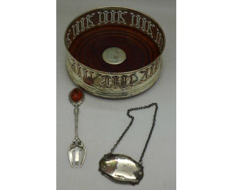 A modern silver Year 2000 coaster, a silver bottle label and a silver fork