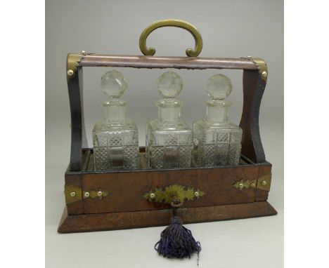 A small walnut, brass mounted three bottle tantalus, with key