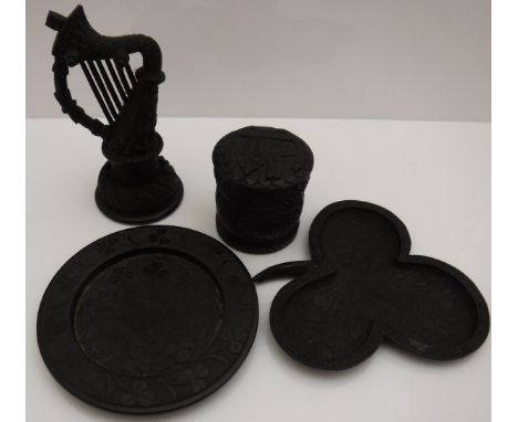 Four pieces of Irish bog oak, one carved as an Irish harp with shamrock, a cylindrical pot and cover, a shamrock shaped pin d