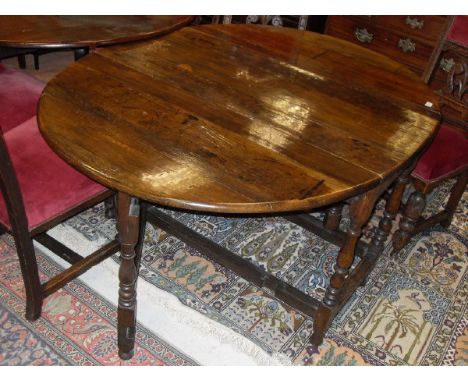 An oak oval gate leg drop leaf dining table in the circa 1700 manner with end drawer raised on baluster turned and ringed leg