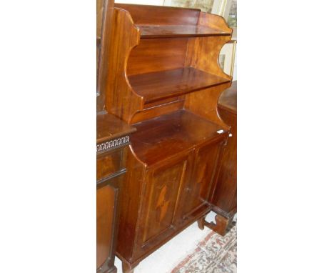 A late Victorian mahogany waterfall bookcase cabinet with three shelves above the two inlaid cupboard doors on tapering sabre