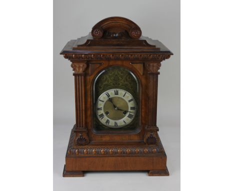 A walnut cased mantel clock, the silvered chapter ring with Roman numerals, the movement stamped Junghans, 51cm, with key