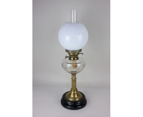 A Victorian brass oil lamp with globular white glass shade, funnel and clear glass well, mounted on black pedestal base, 65.5