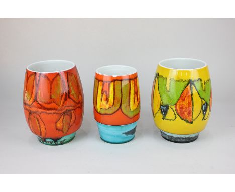 Three Poole Pottery Delphis vases with orange, yellow and green abstract designs, on stepped turquoise bases