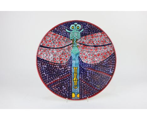 A Poole Pottery charger designed by Tony Morris, decorated with a central dragonfly in red, purple, yellow and shades of blue