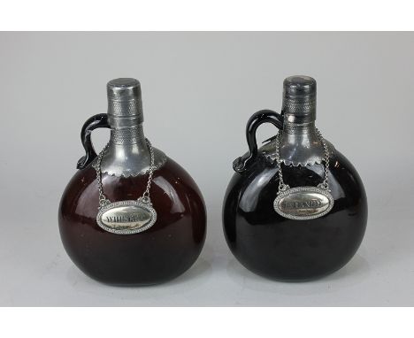 A metal mounted amber glass flask and another similar (with damaged spout), with labels for whisky and brandy (a/f), 19.5cm