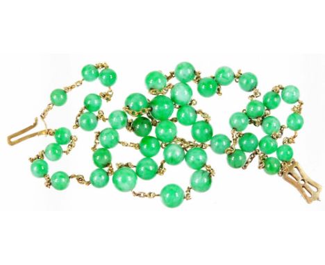 A two row jade necklace, with spherical jade beads, on yellow metal chain, unmarked, with bow design clasp, 42cm L overall.