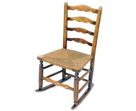 A late 19thC rush seated child's rocking chair, with ladder back, turned supports, turned legs on a rocker base, joined by a 