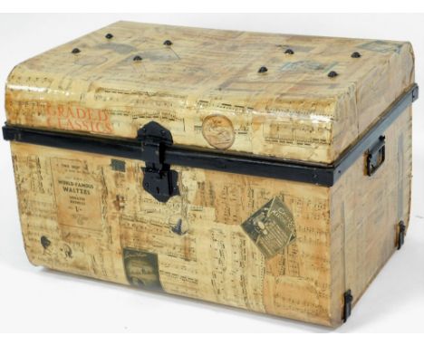 A 20thC tin trunk, over stained with papier mache music score decoration, with carrying handles and domed top, 47cm H, 77cm W