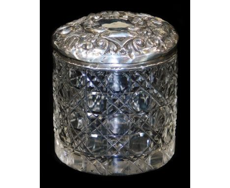 An Edwardian silver and cut glass jar and cover, the lid profusely repousse decorated with scrolls and birds, Birmingham 1905