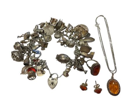 Silver charm bracelet with an extensive collection of novelty silver charms, together with a silver and amber pendant, ring a
