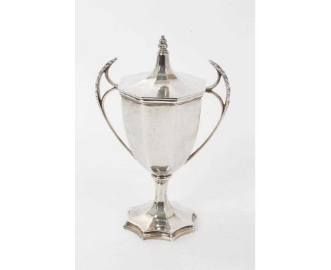 George V silver cup and cover of octagonal form, with twin leaf mounted handles and octagonal slip in cover, on a star shaped
