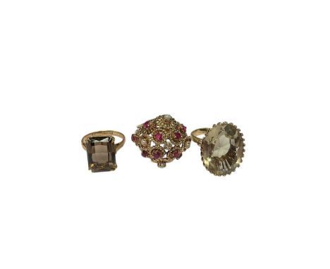 Three gold gem set cocktail rings to include 9ct gold smoky quartz ring, size K½, yellow metal gem set bombé ring, size M and