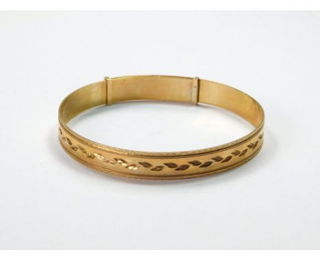 GOLD BANGLE. A 9ct. gold, expandable, engraved bangle. Present internal diameter, 6.3cm. Expands to 7.6cm. Approx. 17.7g. Con