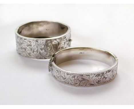 SILVER BANGLES. Two engraved silver, hinged bangles. Widths, 1. & 2.5cm. Condition Report: Both banghles have some shallow de