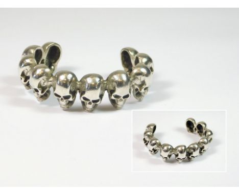 SILVER SKULLS BANGLE. A heavy, cast silver, skulls torque bangle. Approx. 85g. Internal circumference, 13.5cm. Width across, 