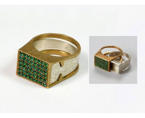 SILVER RING. A brushed silver & silver gilt ring, the top pave-set with green paste stones. The shank designed so that the in