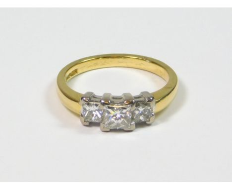 DIAMOND RING. An 18ct. gold, three stone, princess-cut diamond ring, with an 18ct. white gold claw setting. Central diamond a