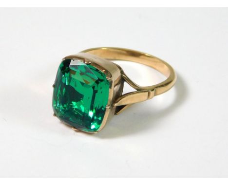 DRESS RING. A late 19th century rose coloured metal ring, set a vivid green rectangular-cut stone, in a closed back setting. 