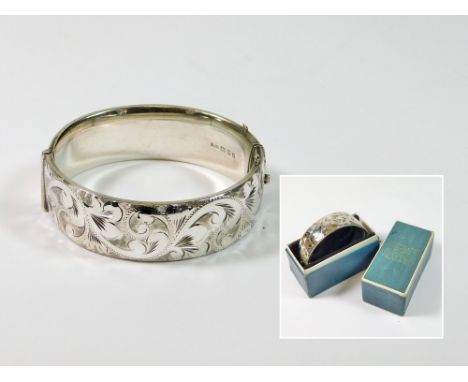 SILVER BANGLE. A mid-1960's, engraved hinged silver bangle. Width 1.8cm. Boxed. Condition Report: Excellent, although box lid