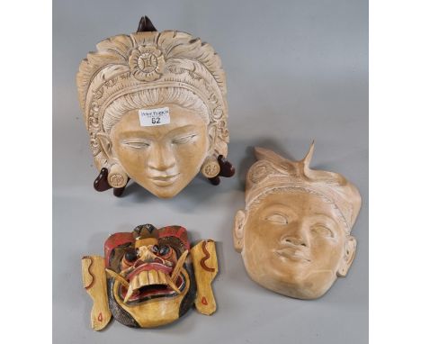 Two similar Balinese carved hardwood maskheads of a young man and lady in headdress and earrings together with a carved Hindu