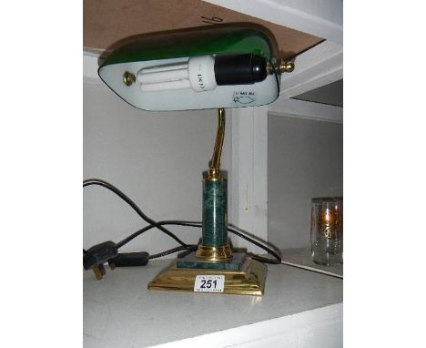 A brass banker's lamp with green glass shade.