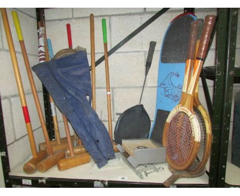 A shelf of tennis rackets, croquet items etc.,