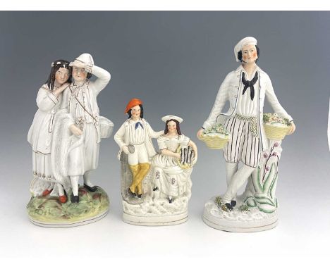 Three Staffordshire figure groups , circa 1865, one modelled as a standing male fruitseller in white enamel painted glaze wit