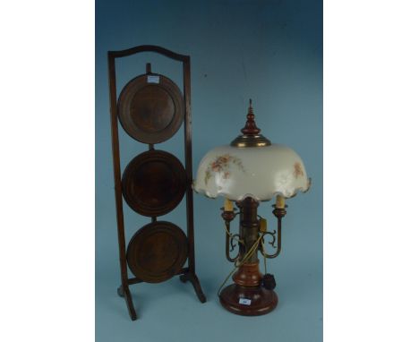 A 20th Century wood and brass three branch table lamp with painted glass shade plus a three tier folding cake stand