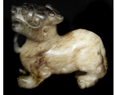 A Chinese jade carving of a Shi or Dog of fo, pale celadon grey brown colouration, modelled crouching with pricked ears and f