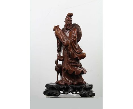 A Chinese carved wood figure of an Immortal standing holding a long scroll bag with crane to one side, inlaid glass eyes with